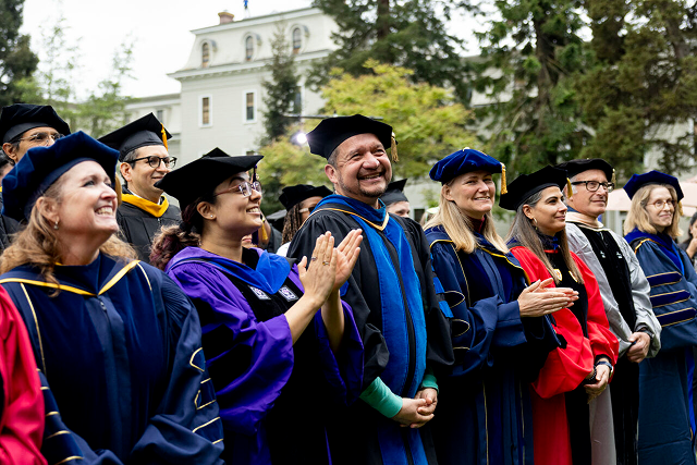 University faculty and staff in academic regalia at graduation ceremony