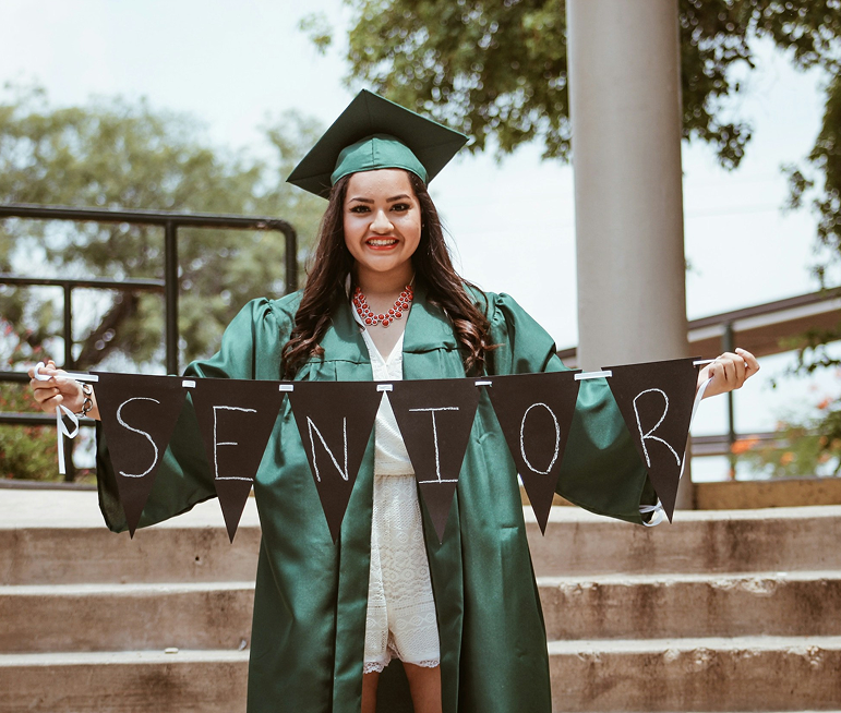 Graduate celebrating with SENIOR banner