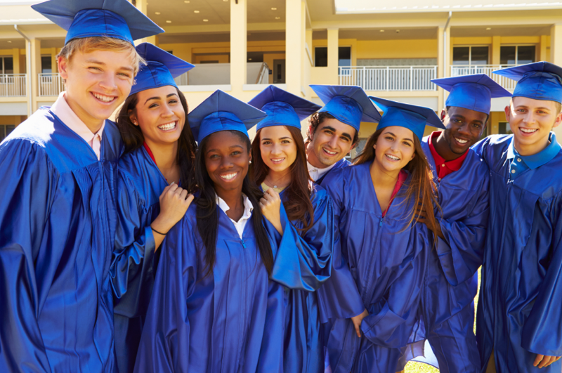 High school graduates in blue caps and gowns celebrating together